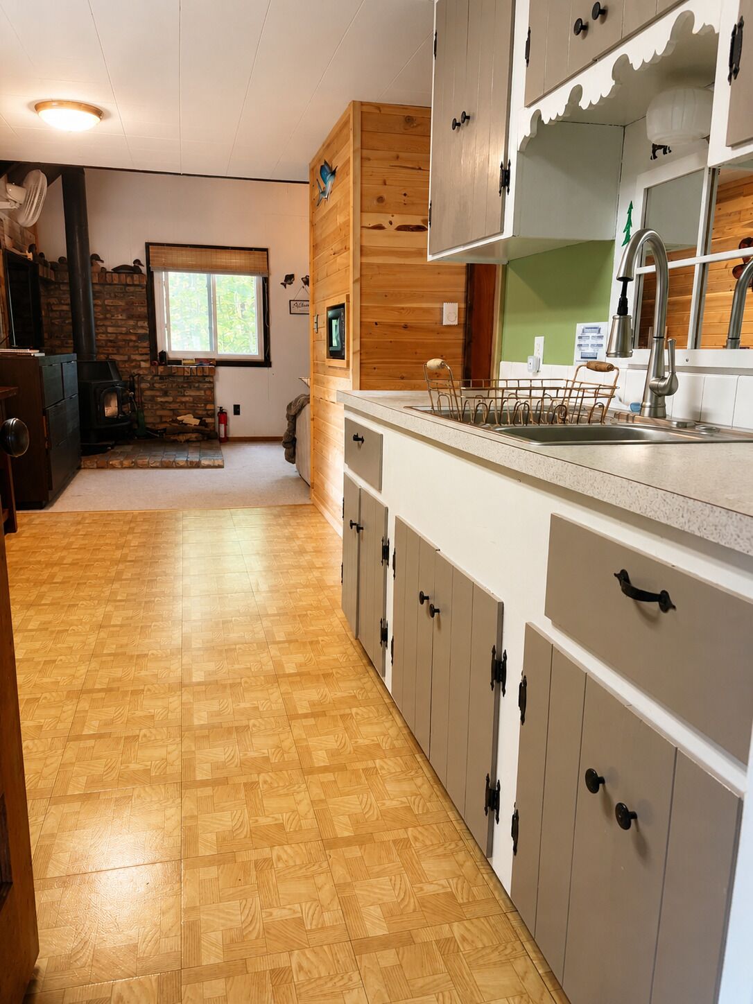 A kitchen with wooden cabinets, a stone fireplace, and a window with a view.