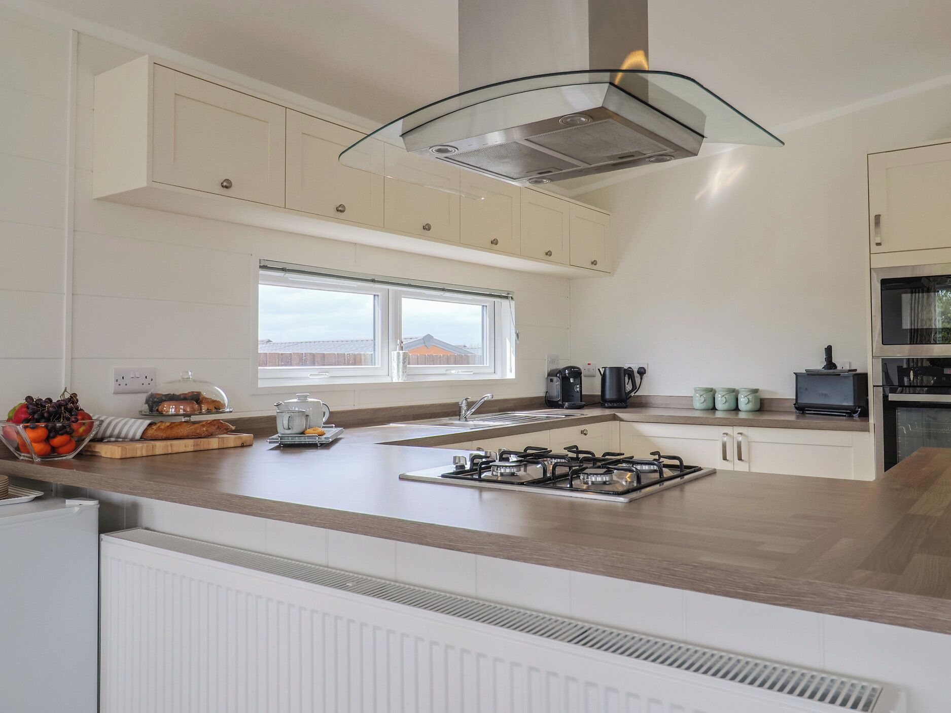 Una cocina moderna con estufa a gas, cafetera y hervidor en la encimera.
