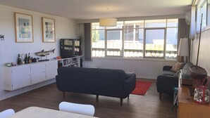 Un soggiorno con divano, televisione e zona pranzo con tavolo e sedie.