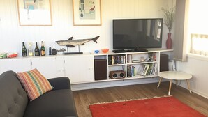 Un soggiorno con un divano, un tappeto rosso, una televisione, una libreria e un tavolino.