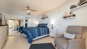 A bedroom with a bed, a chair, a nightstand, a ceiling fan, and a wall with decorative items. - Enjoy This Beautiful 2br/2ba Condo by the Beach at the Sonoran Spa Resort (Puerto Peñasco)