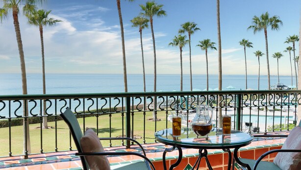 A balcony with a view of the ocean, palm trees, and a pool area. - Enjoy This Beautiful 2br/2ba Condo by the Beach at the Sonoran Spa Resort (Puerto Peñasco)