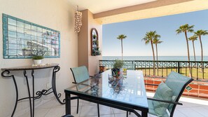 A balcony with a glass table, chairs, and a view of the ocean with palm trees. - Enjoy This Beautiful 2br/2ba Condo by the Beach at the Sonoran Spa Resort (Puerto Peñasco)