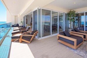 Ein Balkon auf einem Kreuzfahrtschiff mit Sitzgelegenheiten, Glastüren und Blick aufs Meer.