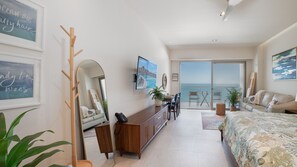 A bedroom with a bed, a desk, a chair, a mirror, and a view of the sea. - One 1403b: Beachfront Bliss Studio in Sandy Beach (Puerto Peñasco)