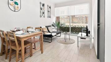 A modern living room with a dining area, a sofa, a coffee table, and a TV.
