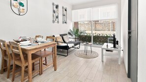 A modern living room with a dining area, a sofa, a coffee table, and a TV.