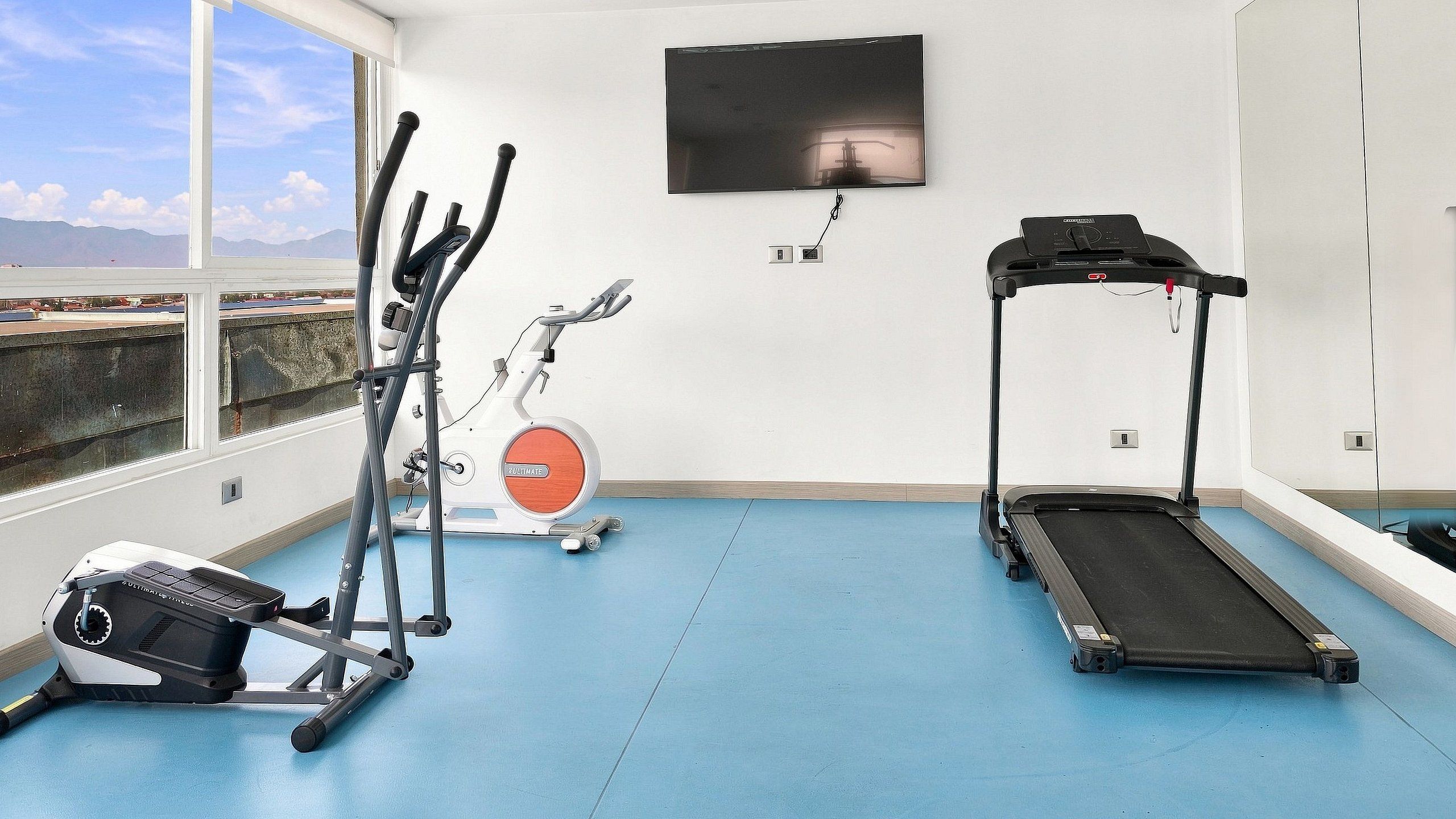 A fitness room with a treadmill, elliptical, and stationary bike.
