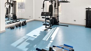A gym with exercise equipment, a blue floor, and a mirror.