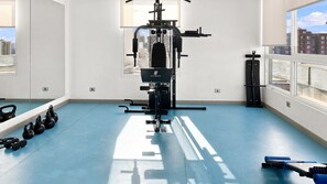 Ein Fitnessraum mit einer Hantelbank, Kettlebells und einer Kabelzugmaschine.