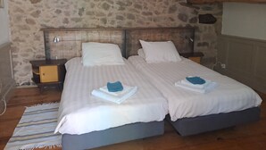 Una cama doble con dos almohadas, cabecera de madera, mesita de noche y mesita auxiliar.