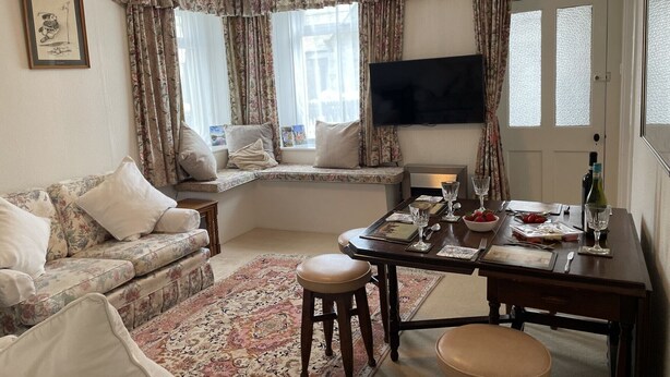 A living room with a sofa, a dining table set for two, a television, and a window with curtains. - Central location, Its our home away from home unique, cosy and charming. (Boat of Garten)