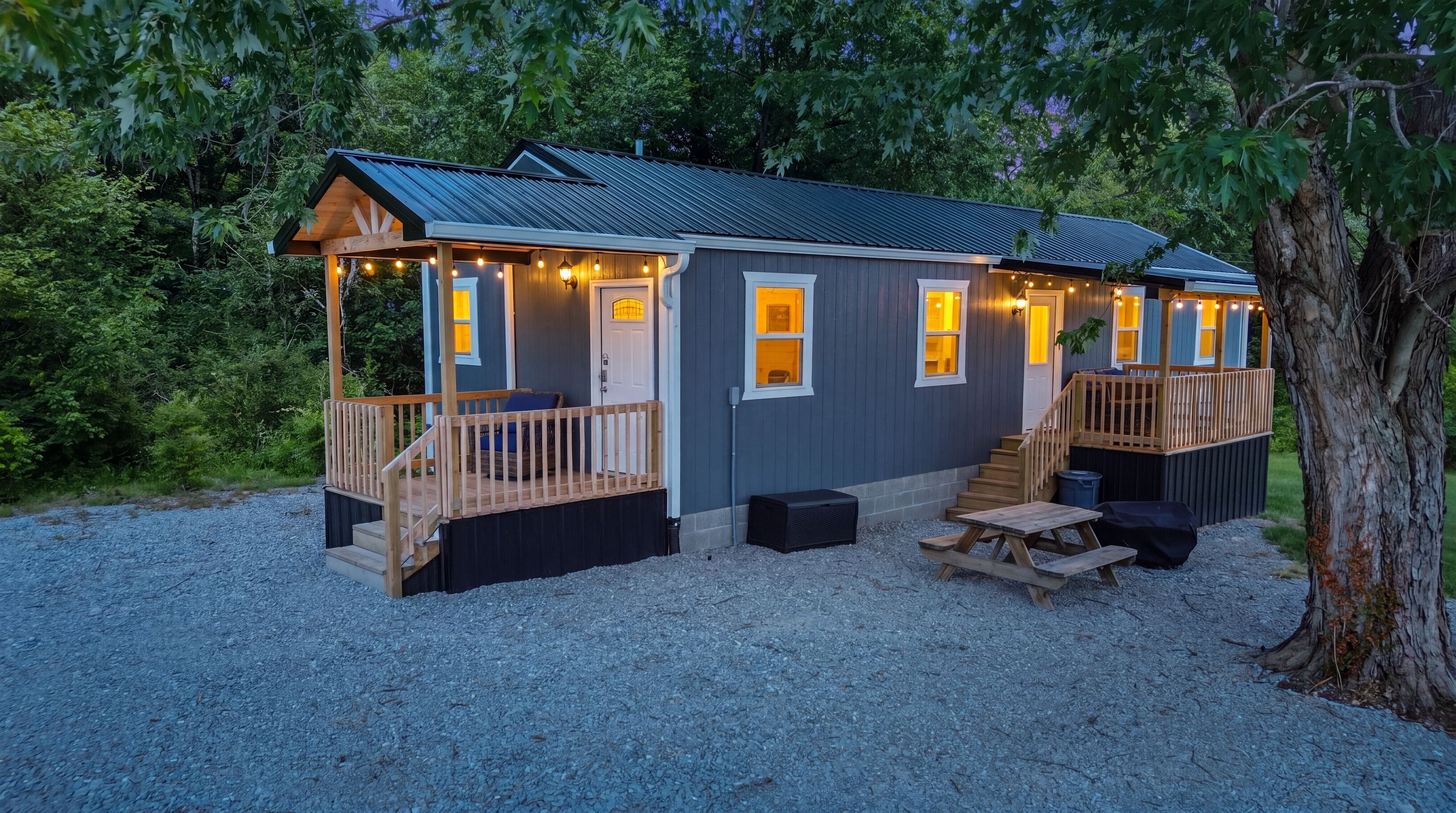 Une cabane avec une véranda, un escalier et une table de pique-nique.