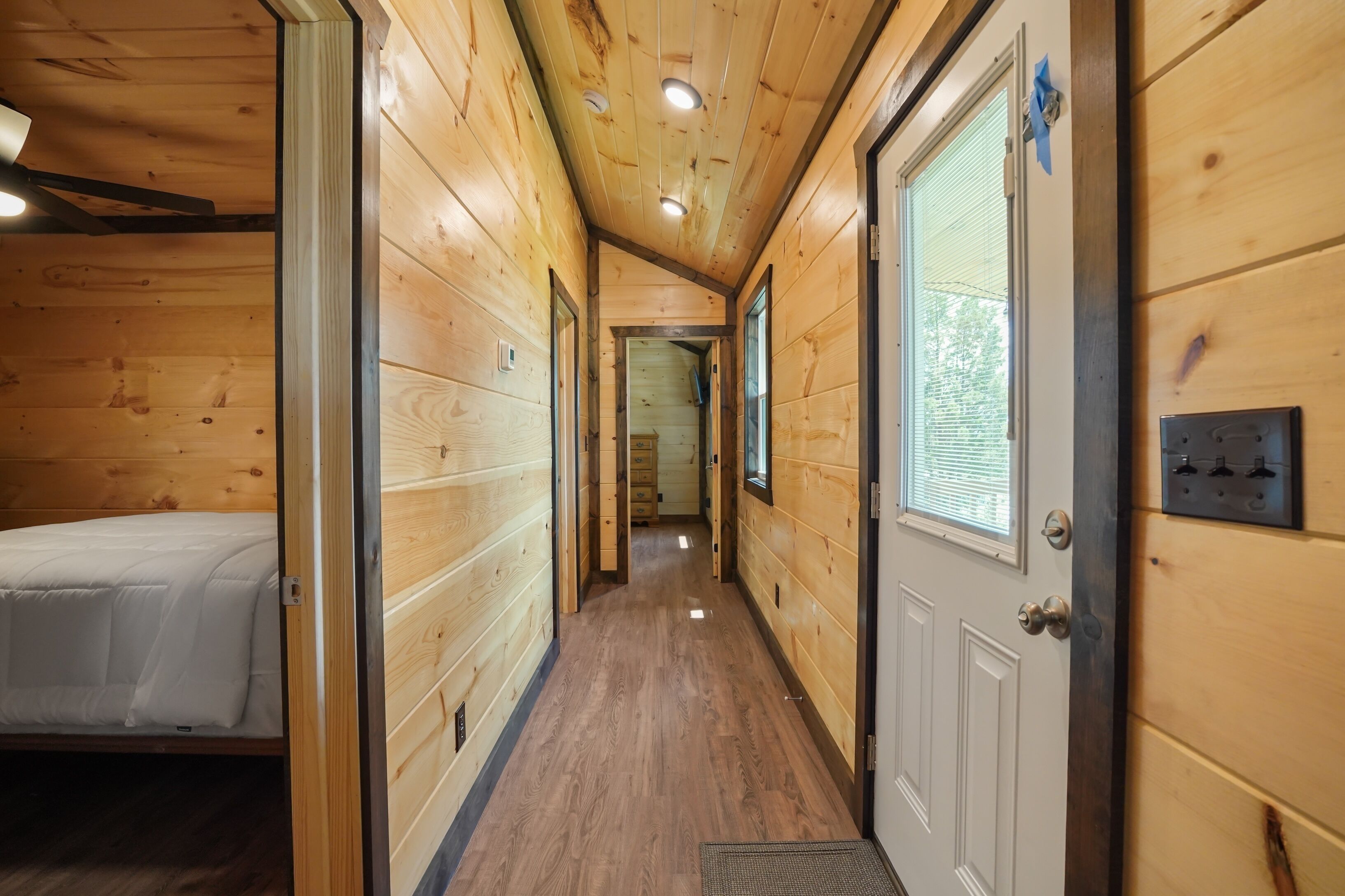 Un couloir étroit aux murs en bois, avec un lit sur le côté gauche.