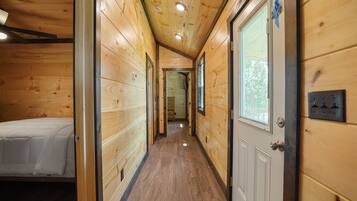 Un couloir étroit aux murs en bois, avec un lit sur le côté gauche.