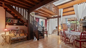 A spacious room with a wooden staircase, a sofa, a dining table with chairs, and a fireplace. - Mas Goya, a peaceful villa on the gentle slopes below the pretty hill-top village of Tourtour. (Tourtour)