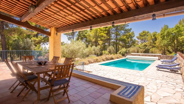 An outdoor pool area with a pergola, wooden chairs, and a table set for dining. - Mas Goya, a peaceful villa on the gentle slopes below the pretty hill-top village of Tourtour. (Tourtour)