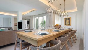 Un espace repas moderne avec une longue table en bois, de nombreuses chaises et des suspensions décoratives en forme d’étoile.