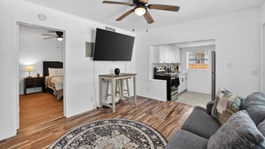 A modern living room with a ceiling fan, a flat-screen TV, a gray sofa, and a patterned rug. - Cozy 1-bedroom house in lovely Tampa with AC - 2706C (Tampa)