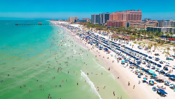 A beach with numerous umbrellas and people, a pier extending into the water, and several high-rise buildings in the background. - Cozy 1-bedroom house in lovely Tampa with AC - 2706C (Tampa)