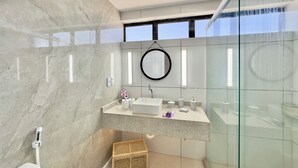 Ein modernes Badezimmer mit Marmorwand, einer Duschkabine aus Glas und einem integrierten Waschbecken mit Spiegel.