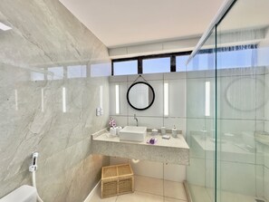 A modern bathroom with a marble wall, a glass shower enclosure, and a built-in sink with a mirror. - Al Mare Residencial (Fortaleza)