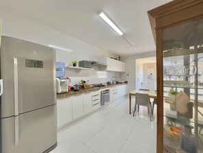 A modern kitchen with a refrigerator, coffee maker, and a water dispenser. - Al Mare Residencial (Fortaleza)