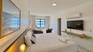 Ein Hotelzimmer mit Bett, Fernseher, Hängematte und einem großen Fenster mit Blick.