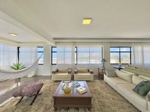 A spacious living room with a large window, a hammock, and a view of the city. - Al Mare Residencial (Fortaleza)