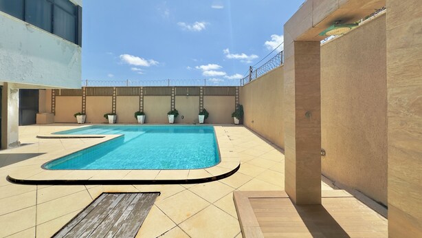 Ein Poolbereich auf dem Dach mit blauem Himmel, einem Pool und Kübelpflanzen.