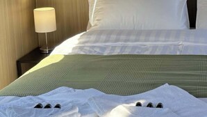Une chambre d’hôtel avec un lit, des oreillers, une table de chevet et une lampe.