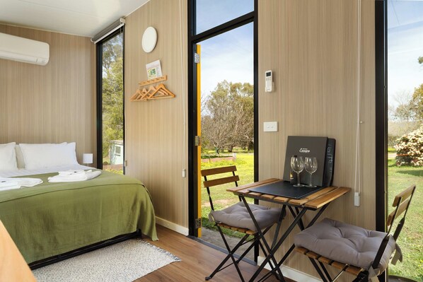 A modern bedroom with a bed, a desk with a chair, and a view of the outdoors.