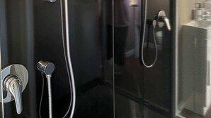 Une salle de bain moderne dotée d’une douche à parois de verre, d’un pommeau de douche à main, d’un robinet mural et d’un porte-serviettes avec une serviette blanche.