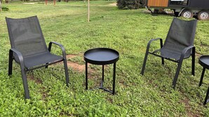 Un terrain de camping avec deux chaises noires et une petite table ronde.