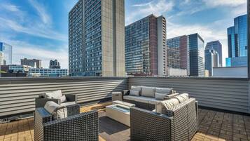 A rooftop terrace with outdoor furniture and a city skyline in the background.