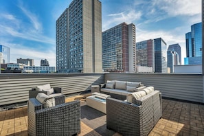 A rooftop terrace with outdoor furniture and a city skyline in the background.