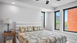 A bedroom with a bed, bedside tables, a ceiling fan, and large windows. - RoofTop - Sleeps 12 - Downtown CLE (Cleveland)