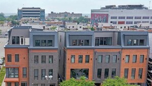 A multi-story building with a modern architectural design, featuring a mix of brick and metal facades, large windows, and a flat roof. - RoofTop - Sleeps 12 - Downtown CLE (Cleveland)