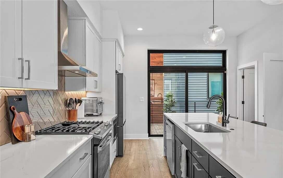 A modern kitchen with white cabinetry, a gas stove, and a large island with a sink.