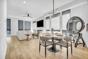 A modern living room with a dining area, large windows, and a round mirror. - Rooftop Deck | Downtown CLE | Near ClevelandClinic (Cleveland)