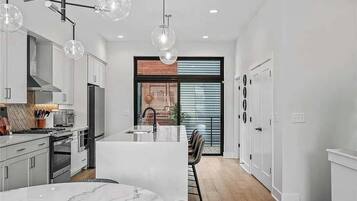 A modern kitchen with white cabinetry, a central island, and pendant lighting.