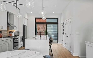 A modern kitchen with white cabinetry, a central island, and pendant lighting.