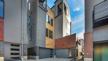 A modern multi-story residential building with a mix of siding and brickwork, a central courtyard, and a garage.
