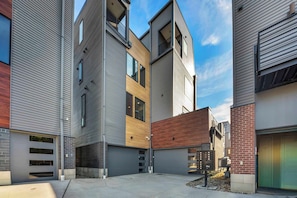 A modern multi-story residential building with a mix of siding and brickwork, a central courtyard, and a garage.