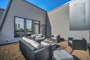 A rooftop terrace with a modern outdoor seating area, including a sofa and chairs, and a glass-top table. - Rooftop Deck | Downtown CLE | Near ClevelandClinic (Cleveland)