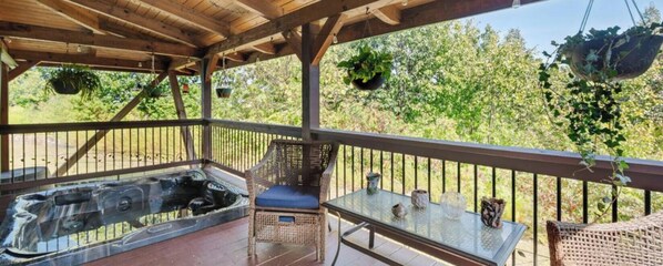 A covered outdoor area with a hot tub, wicker furniture, and hanging plants. - Secluded spacious 3-bedroom 2 floor cabin beautiful mountain views. (Newport)