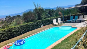 A rectangular swimming pool with a clear blue water, surrounded by a grassy area and a row of white lounge chairs. - Bellavista (Lastra a Signa)