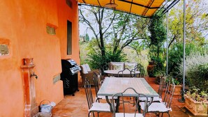 An outdoor patio with a long table and chairs, a grill, and potted plants. - Bellavista (Lastra a Signa)