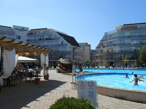 Ein Hotel mit Schwimmbad, Sitzgelegenheiten im Freien und einem Rettungsschwimmer-Schild.
