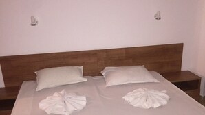 Ein ordentlich bezogenes Bett mit Kissen, einem Holzkopfteil und einem Nachttisch.